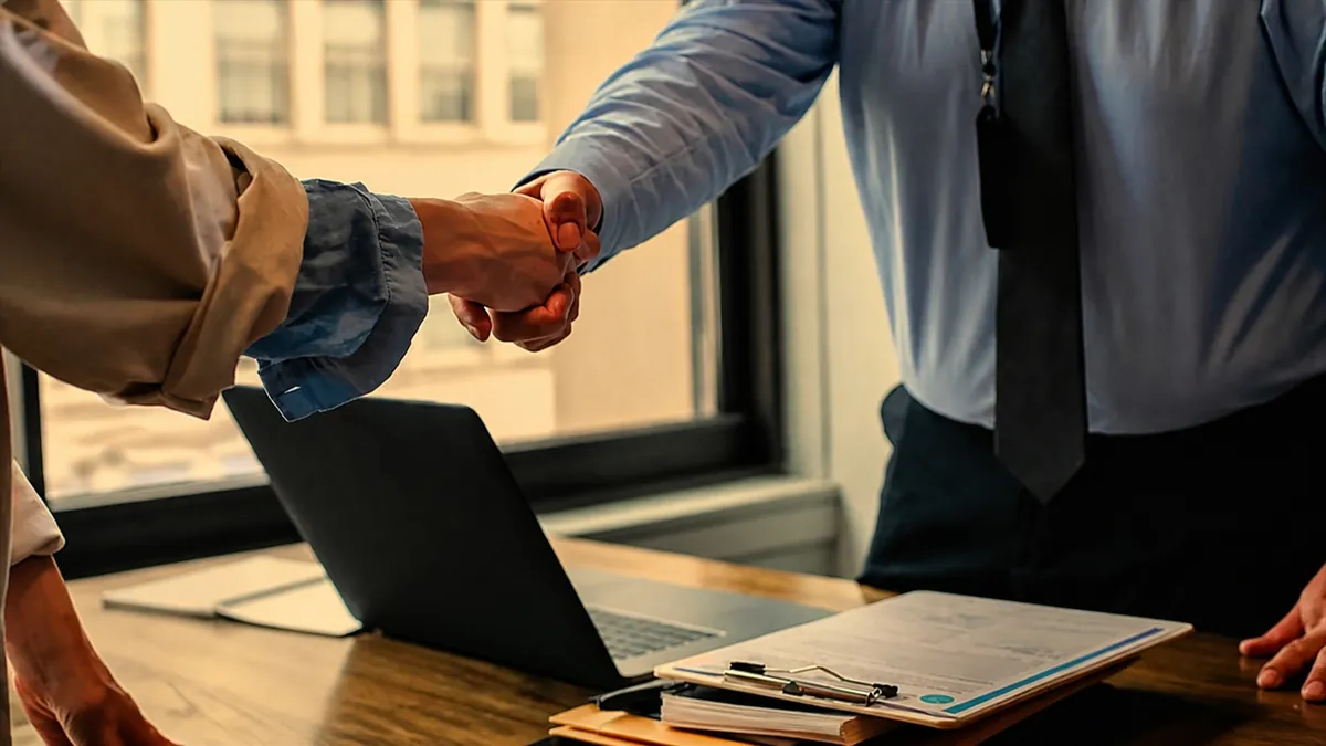 Business partners handshake over laptop