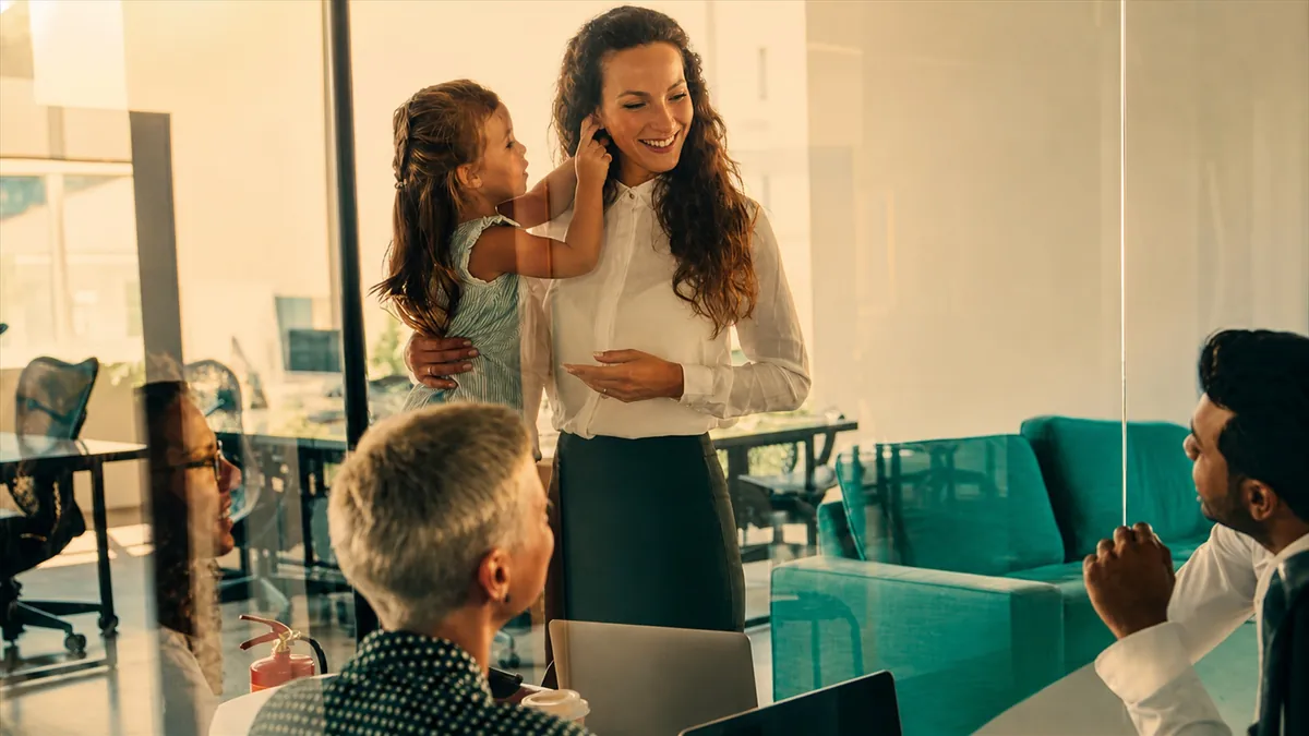 Businesswoman holding child during office meeting